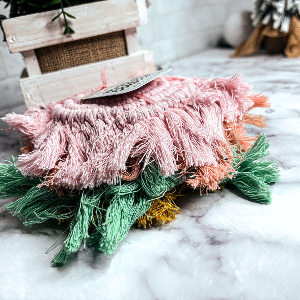 Layered braided rope tassel coasters with pink, green, and small yellow accents