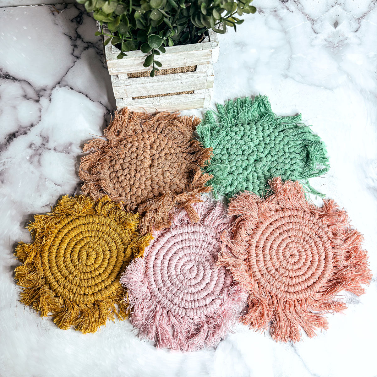 Braided rope tassel coasters featuring teal, brown, yellow, blush pink, and peach tones