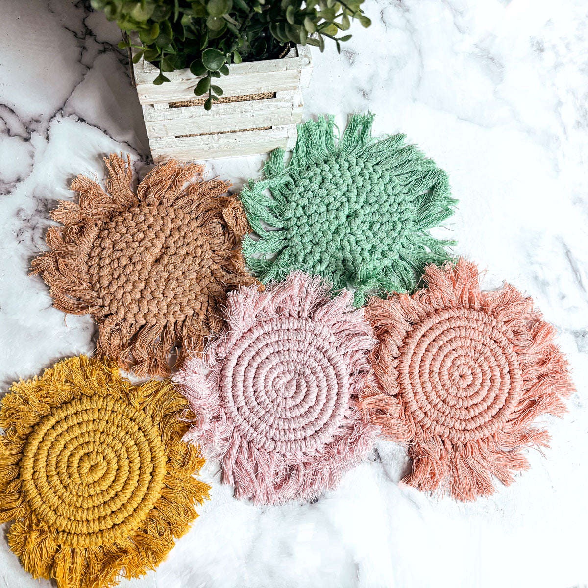 Assorted round braided rope coasters with tassels in tan, yellow, pink, coral, green