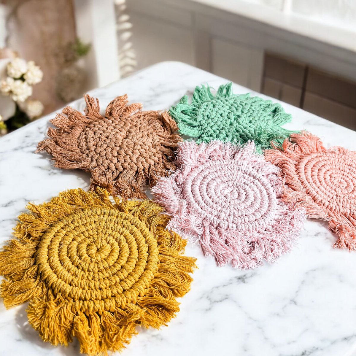 Mixed-color braided rope coasters—tan, green, pink, and yellow—with tassels