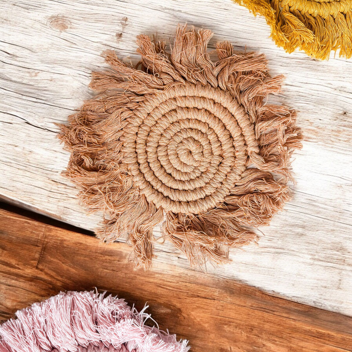 Close-up braided rope tassel coaster in tan-brown with circular spiral and fringe