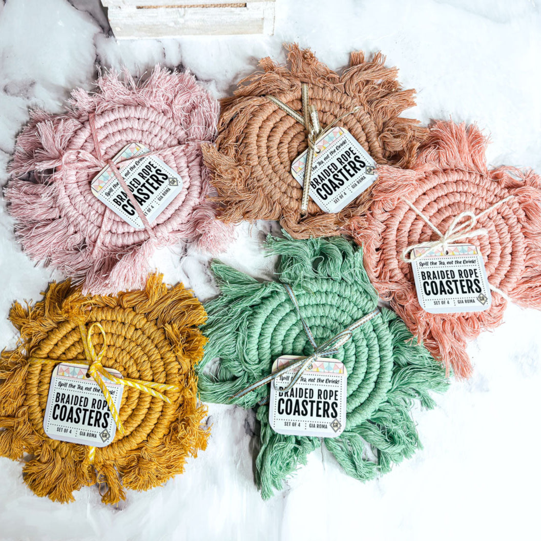 Braided rope tassel coasters in pink, brown, orange, green, and yellow on a light surface