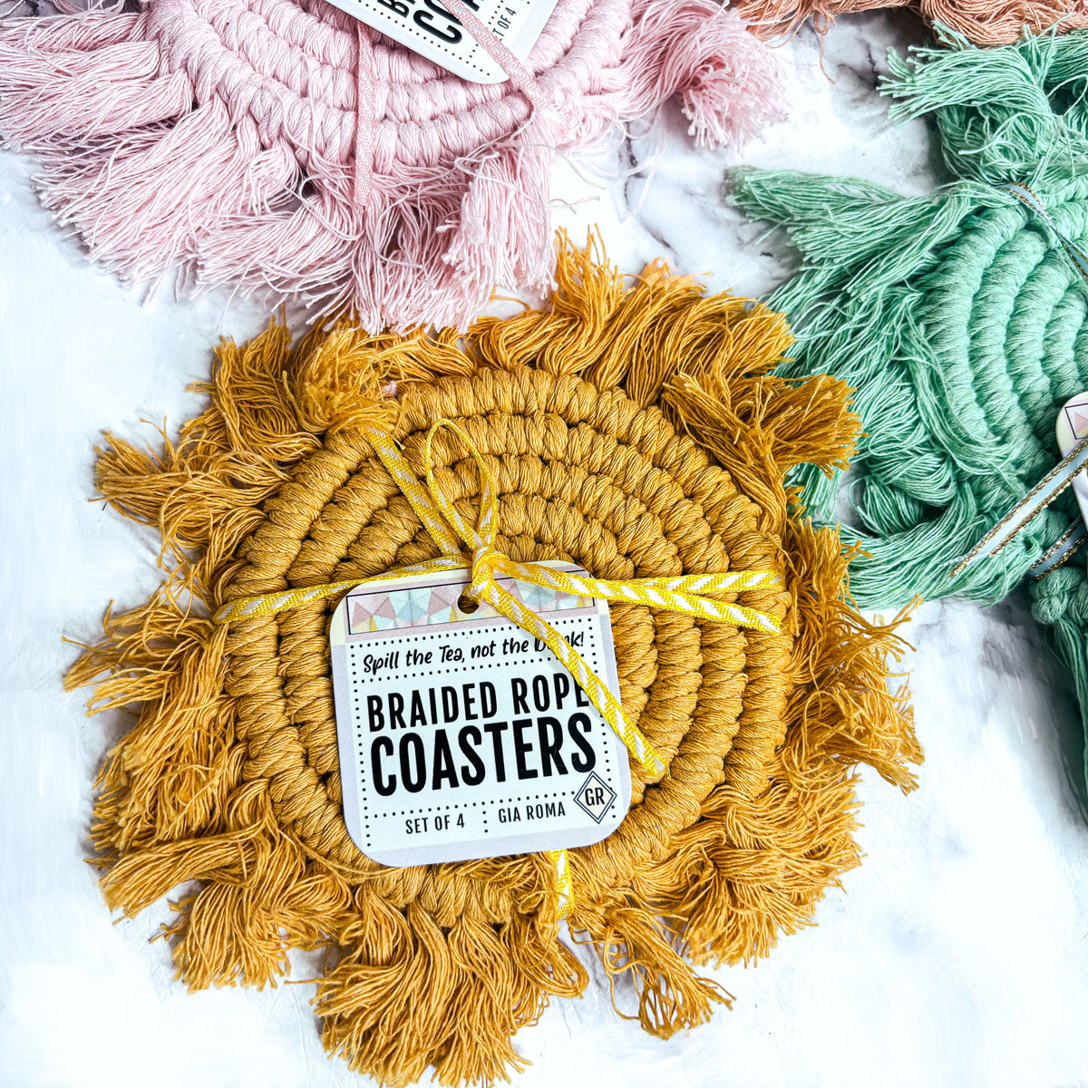 Mustard, mint green, and pink braided rope coasters with tassels and spiral centers