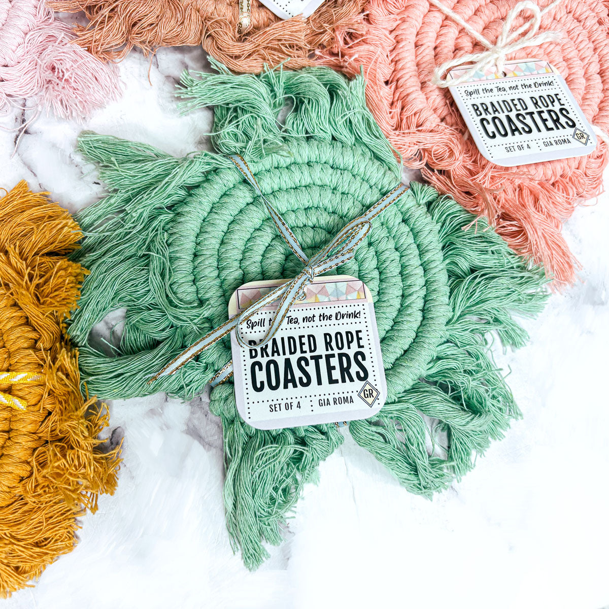 Mint green round braided rope coaster with tassels, paired with coral and gold
