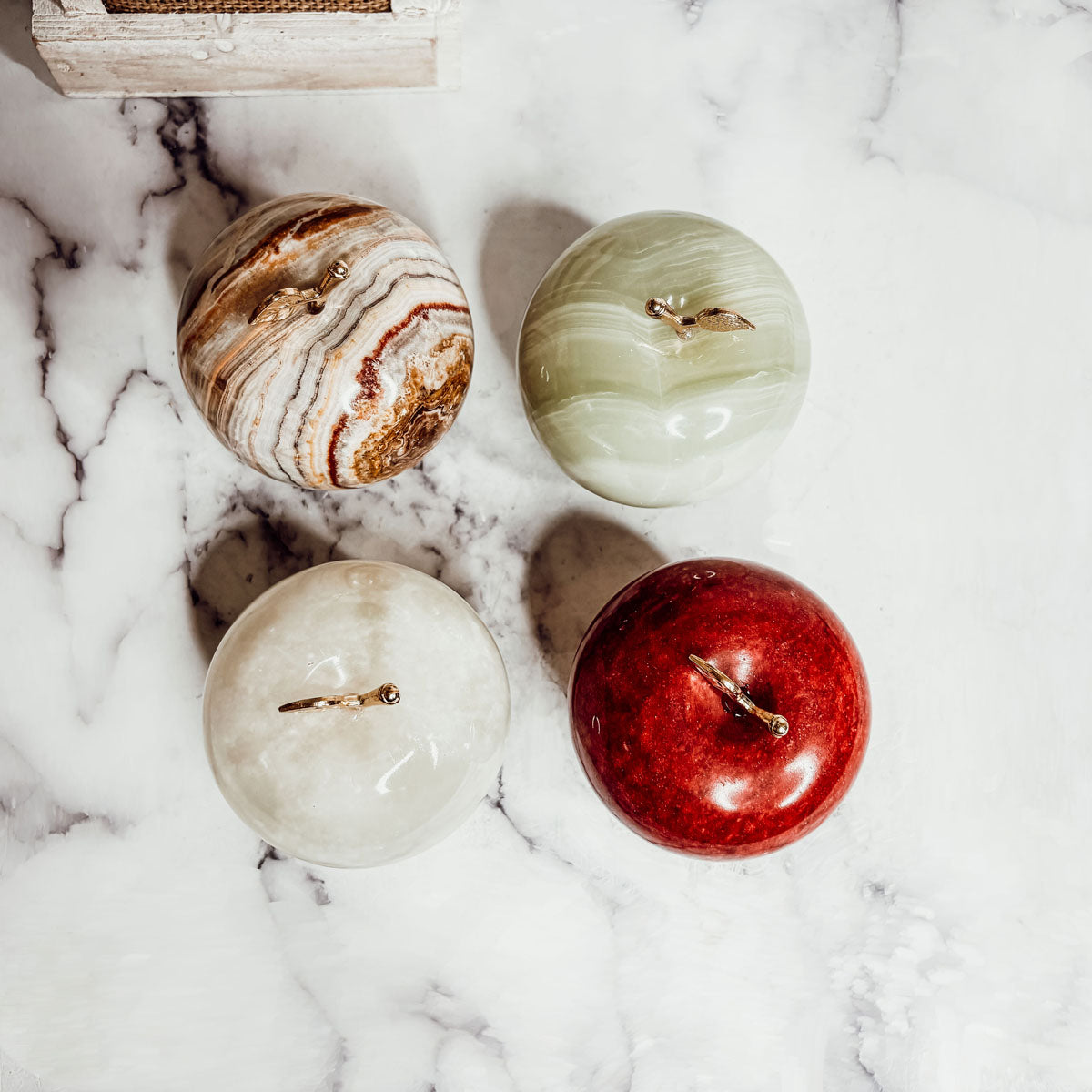 Five heart-shaped paperweights on surface: brown marbled, pale green, cream, and red.