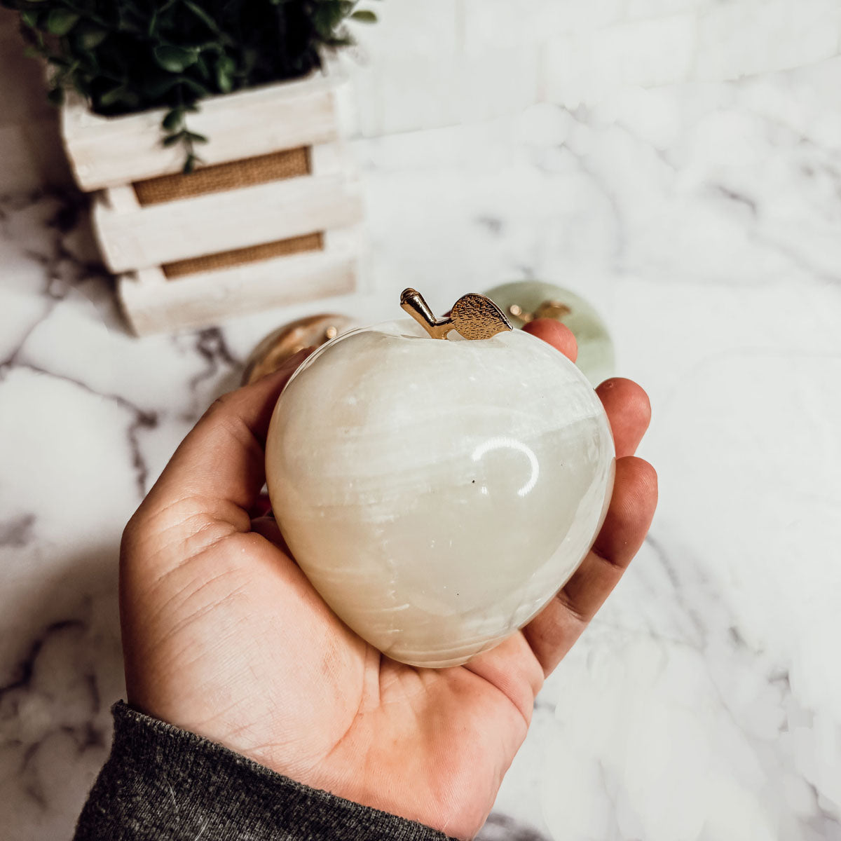 Cream white heart-shaped paperweight with gold top clasp and glossy surface.