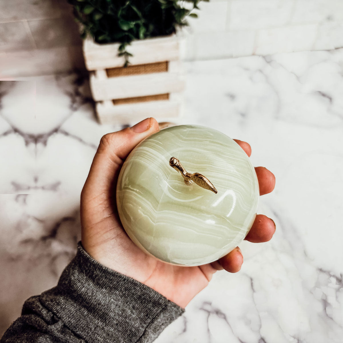 Light green heart-shaped paperweight with gold top clasp and curved stone swirls.