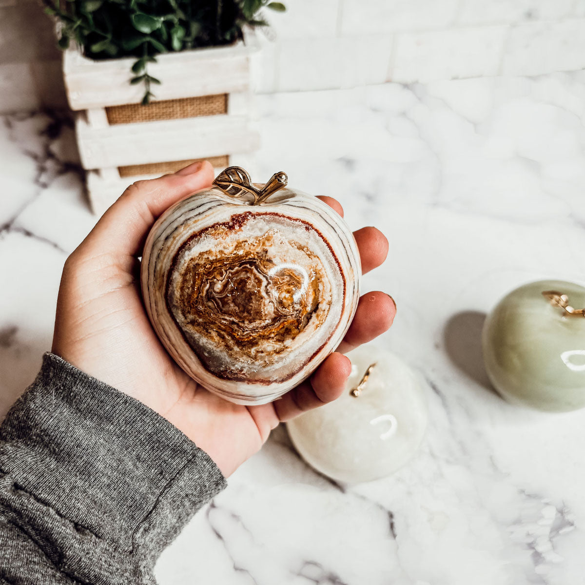 Hand holding a heart-shaped stone apple paperweight with gold-tone top detail