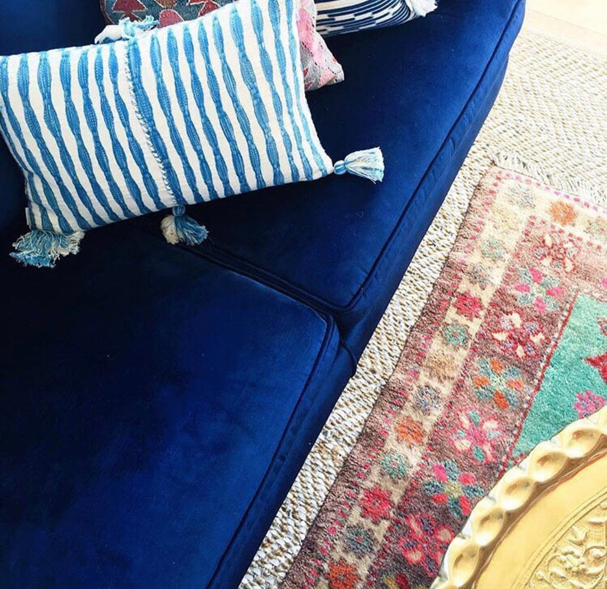 Blue sofa with blue and white striped pillows featuring tassel corners