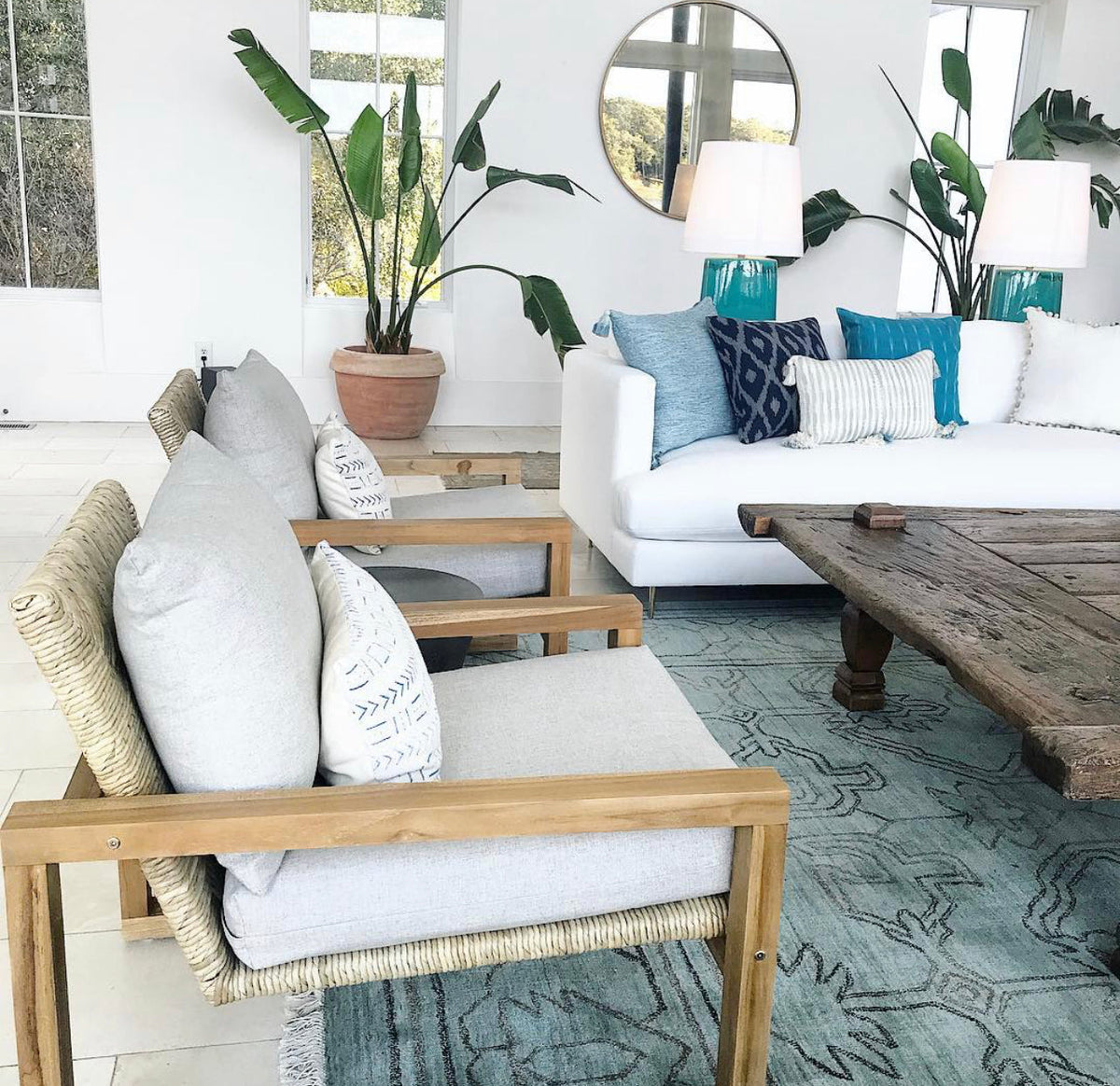 White outdoor sofa with blue striped pillows and tassel-trim corners