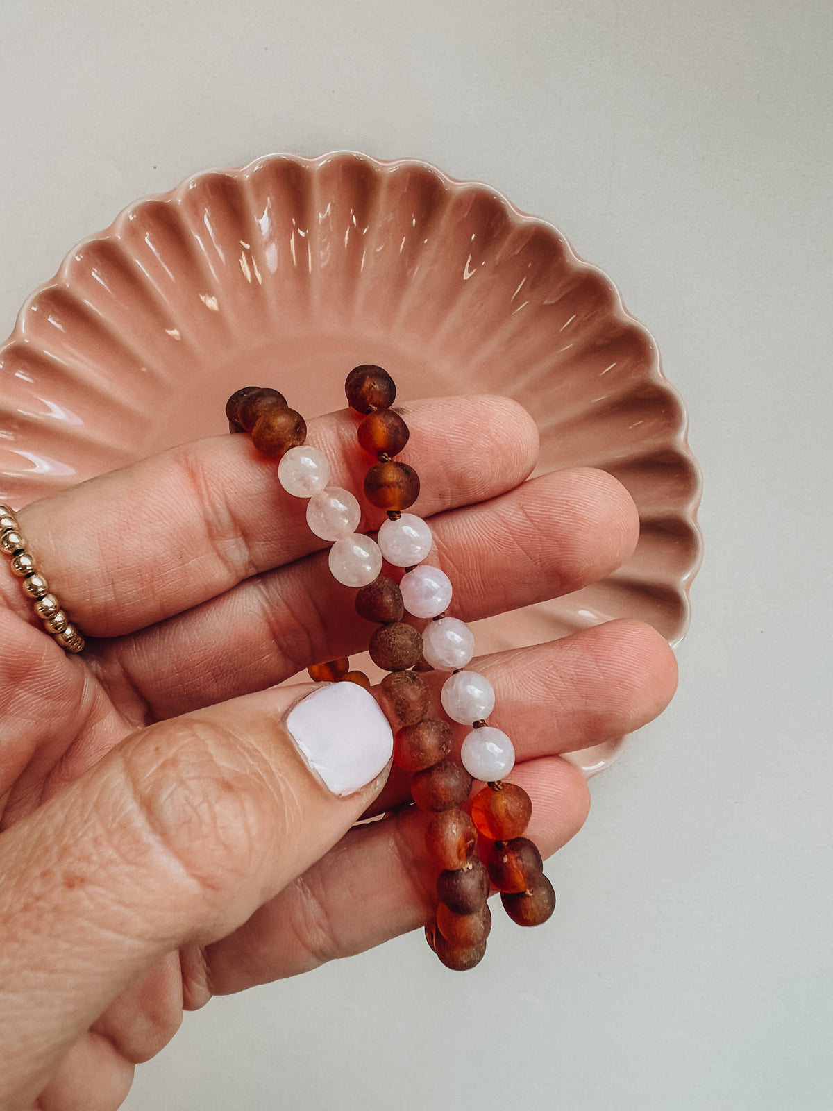 Amber and rose quartz bead bracelet with brown and white beads on hand