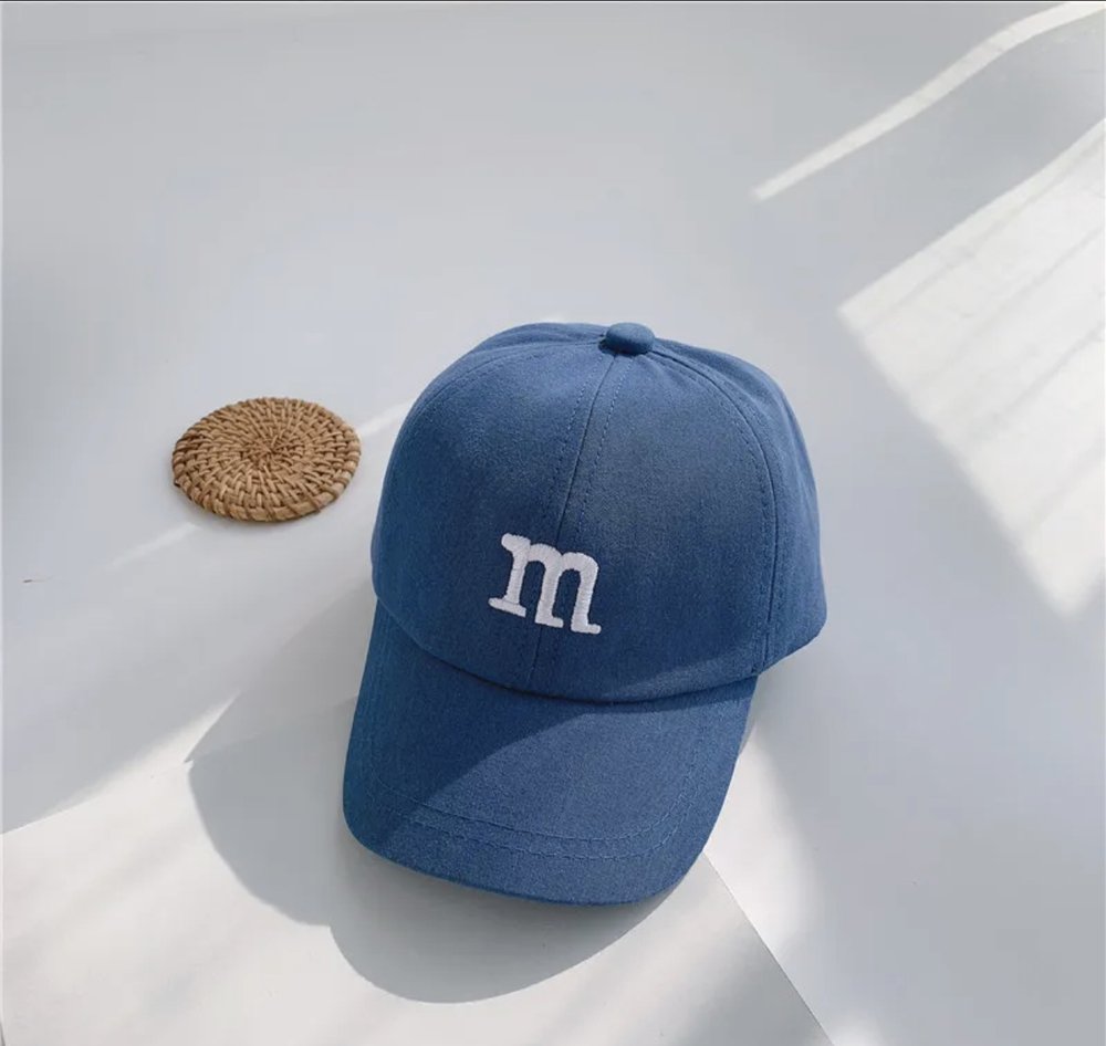 Kids baseball cap in blue with a raised “m” logo on the front
