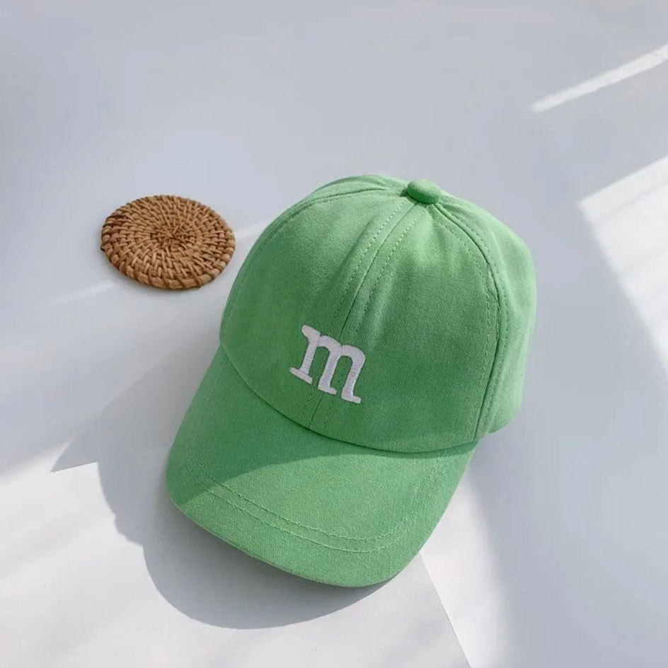 Kids baseball cap in green with an “m” logo on the front