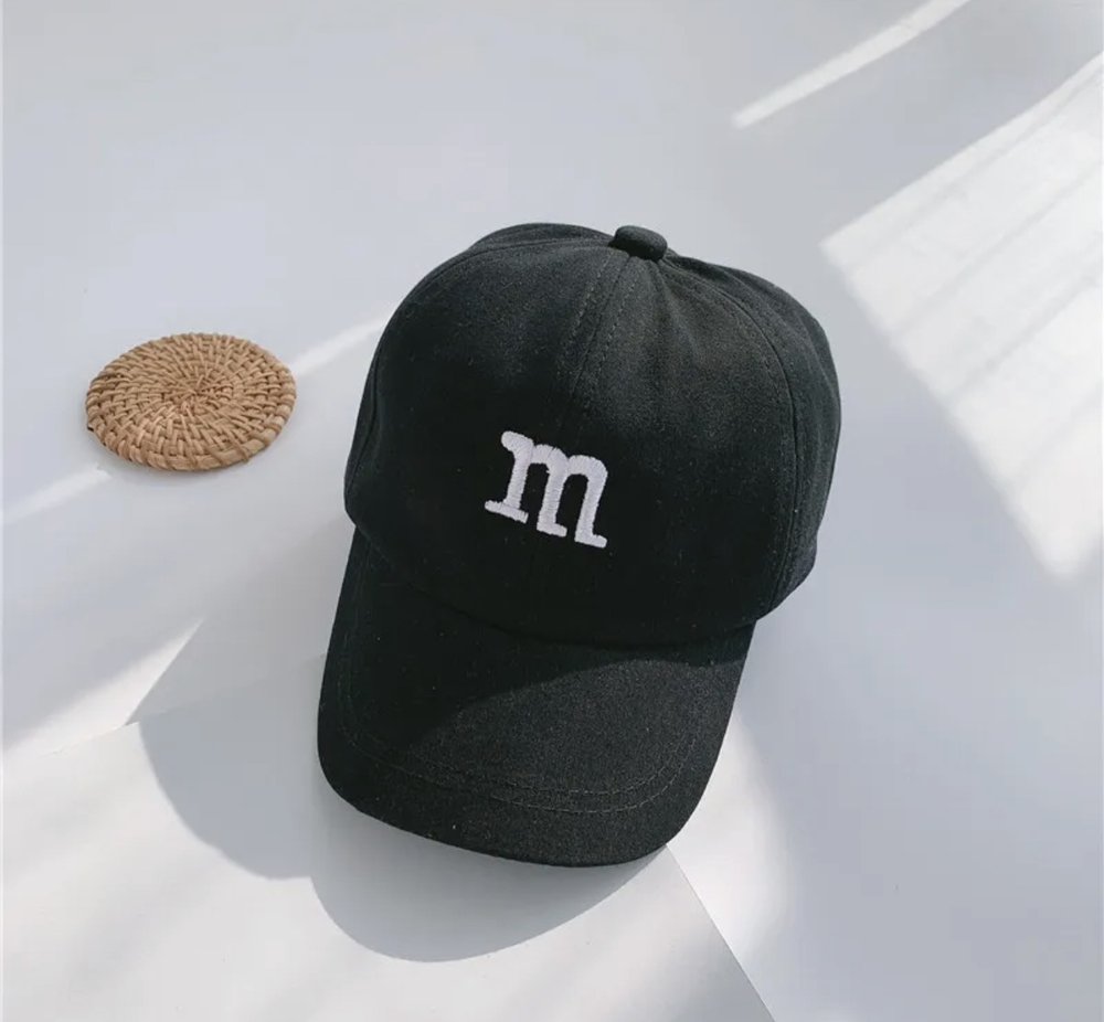 Kids baseball cap in dark green with a white “m” logo on the front