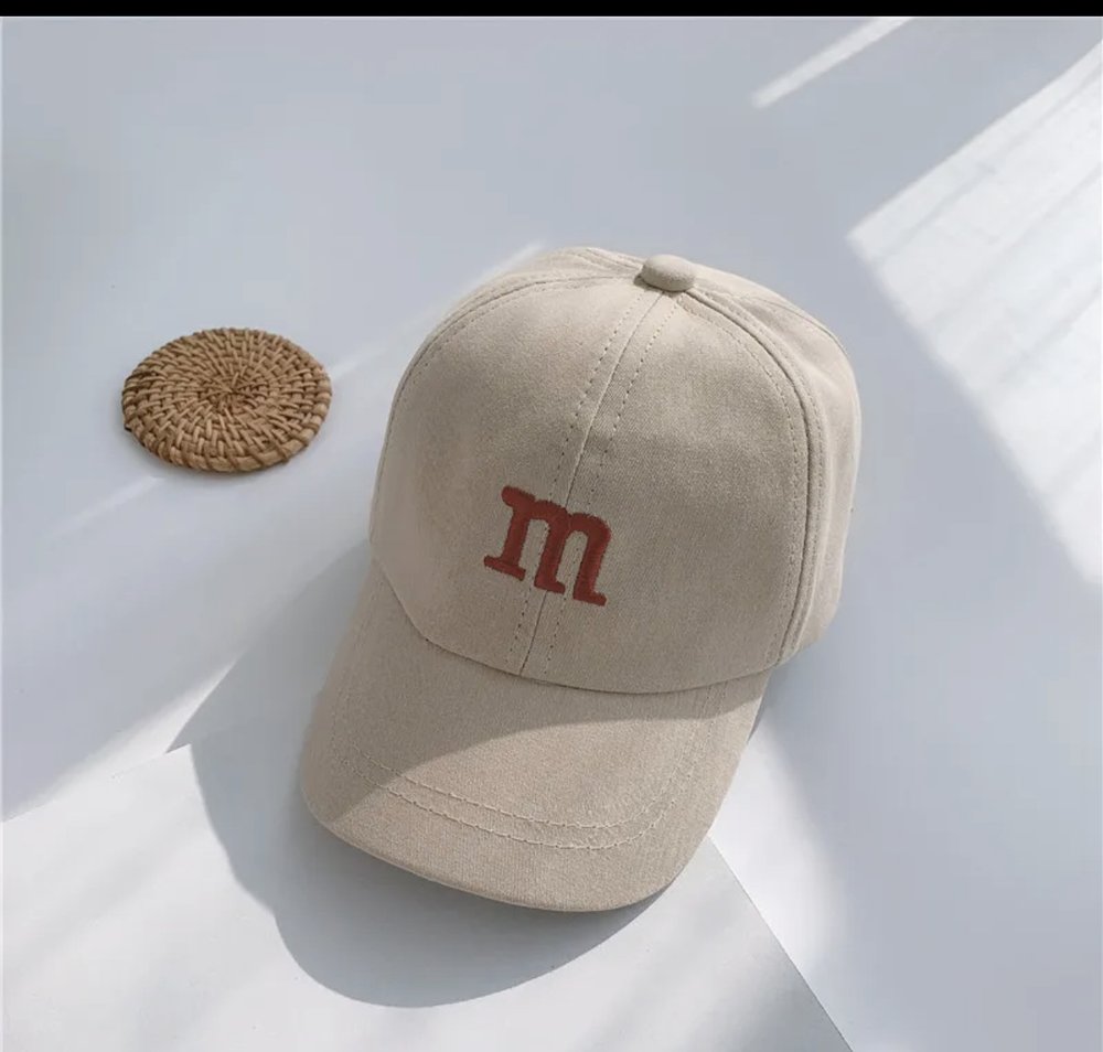 Kids baseball cap in beige with an “m” logo on the front