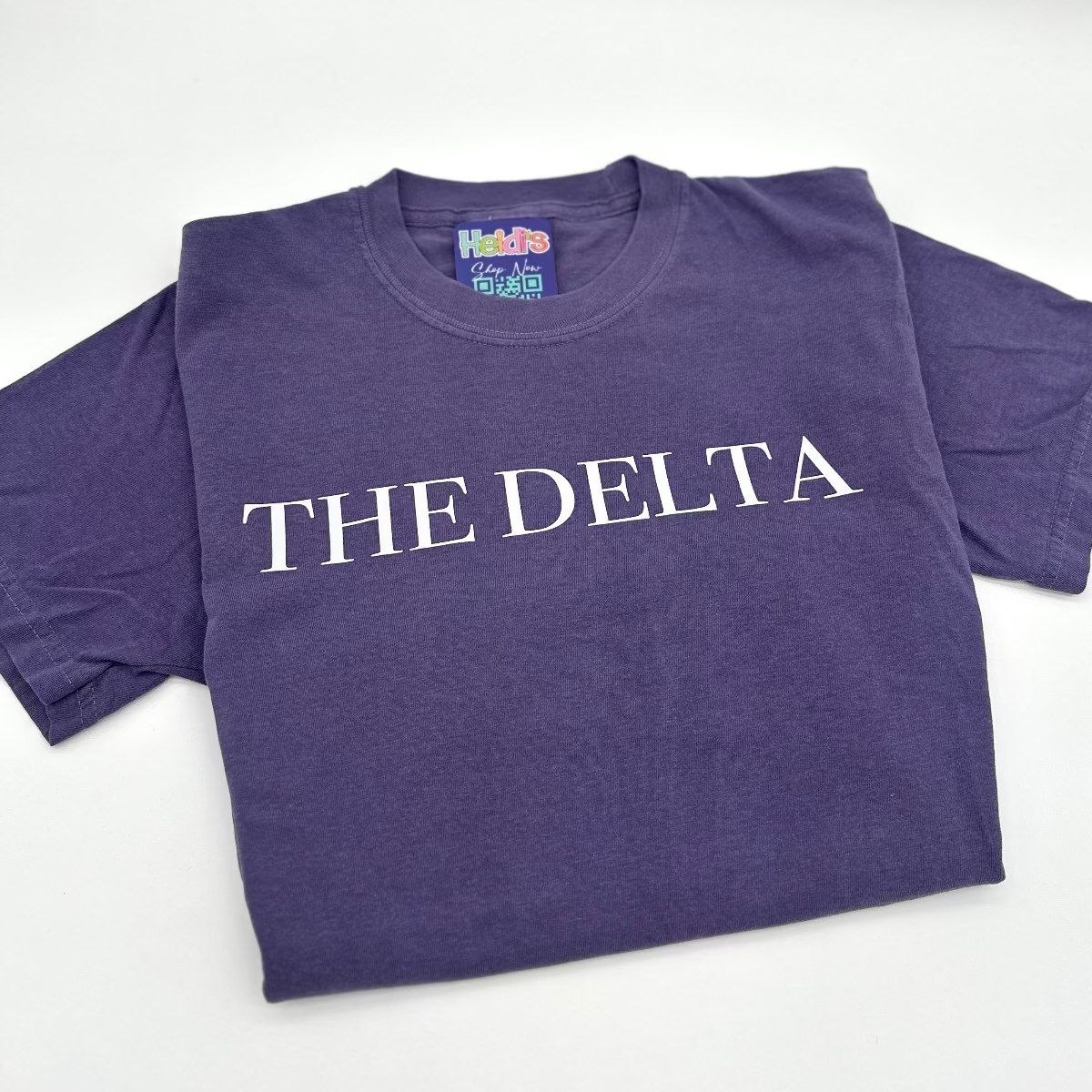 Purple crew-neck graphic T-shirt with white “THE DELTA” text on the chest.
