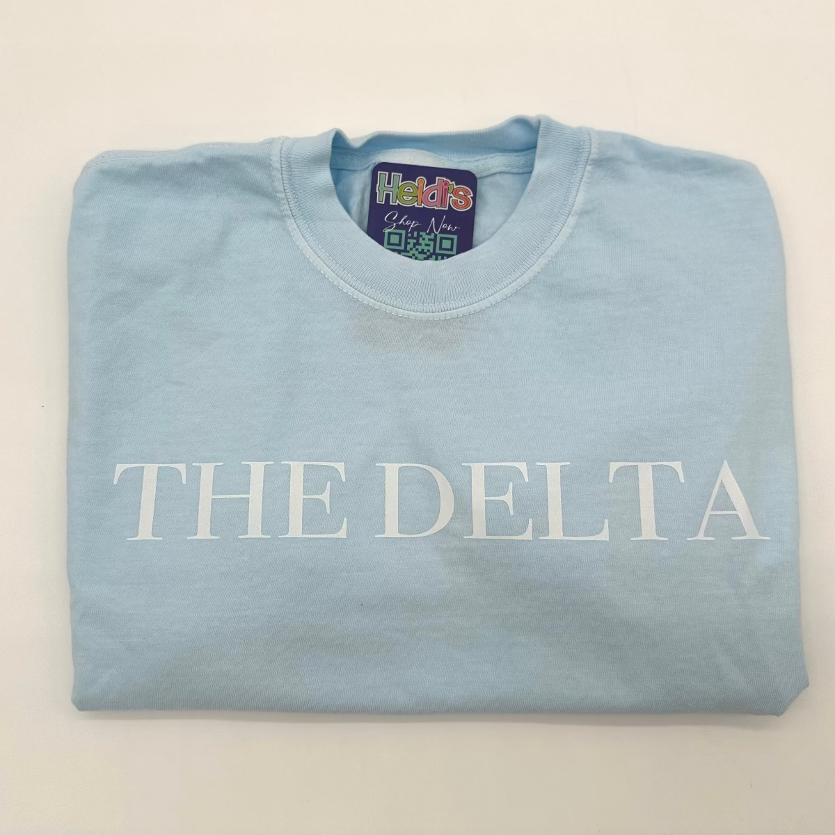 Light blue crew-neck graphic T-shirt with white “THE DELTA” lettering across chest.