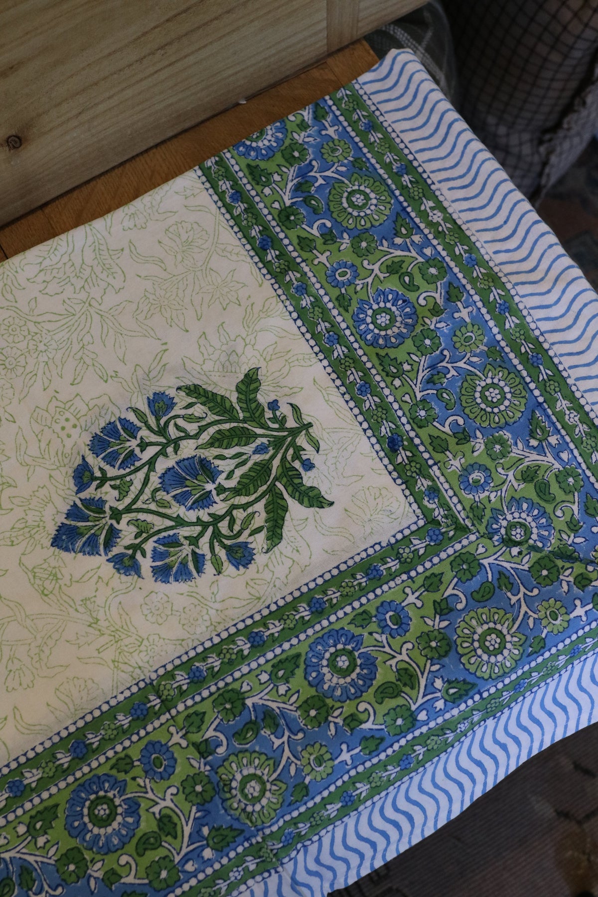 Cream tablecloth with green and blue floral medallions and striped edge