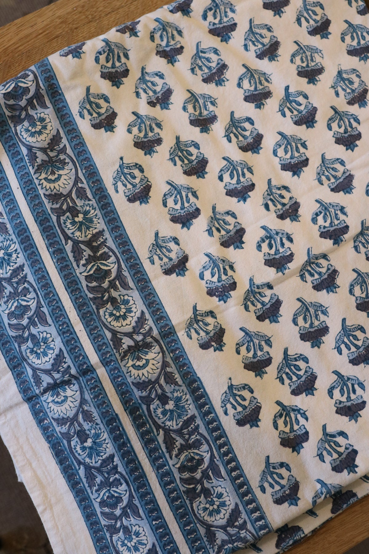 Cream tablecloth with blue animal-like motifs and ornate side border