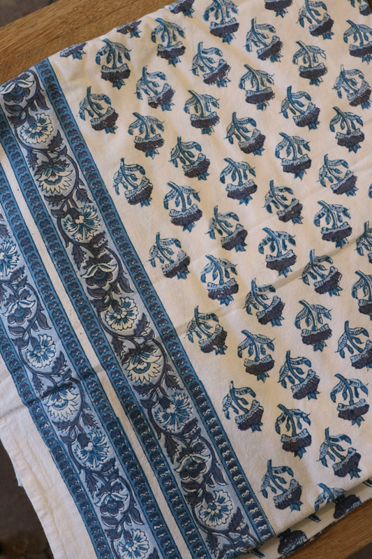 Cream tablecloth with blue animal-like motifs and ornate side border