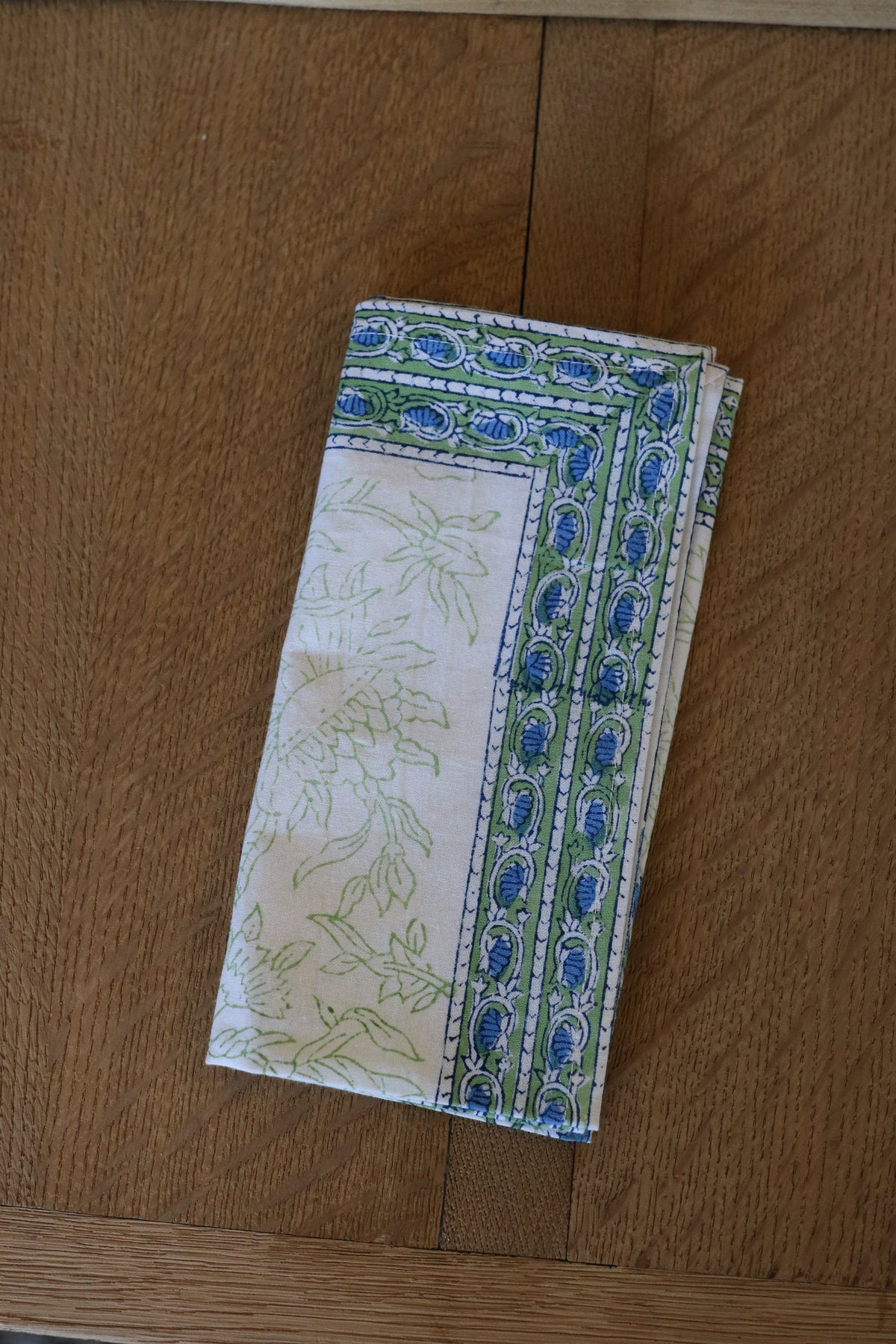 Botanical garden napkin in white with blue border detailing and botanical line pattern, folded