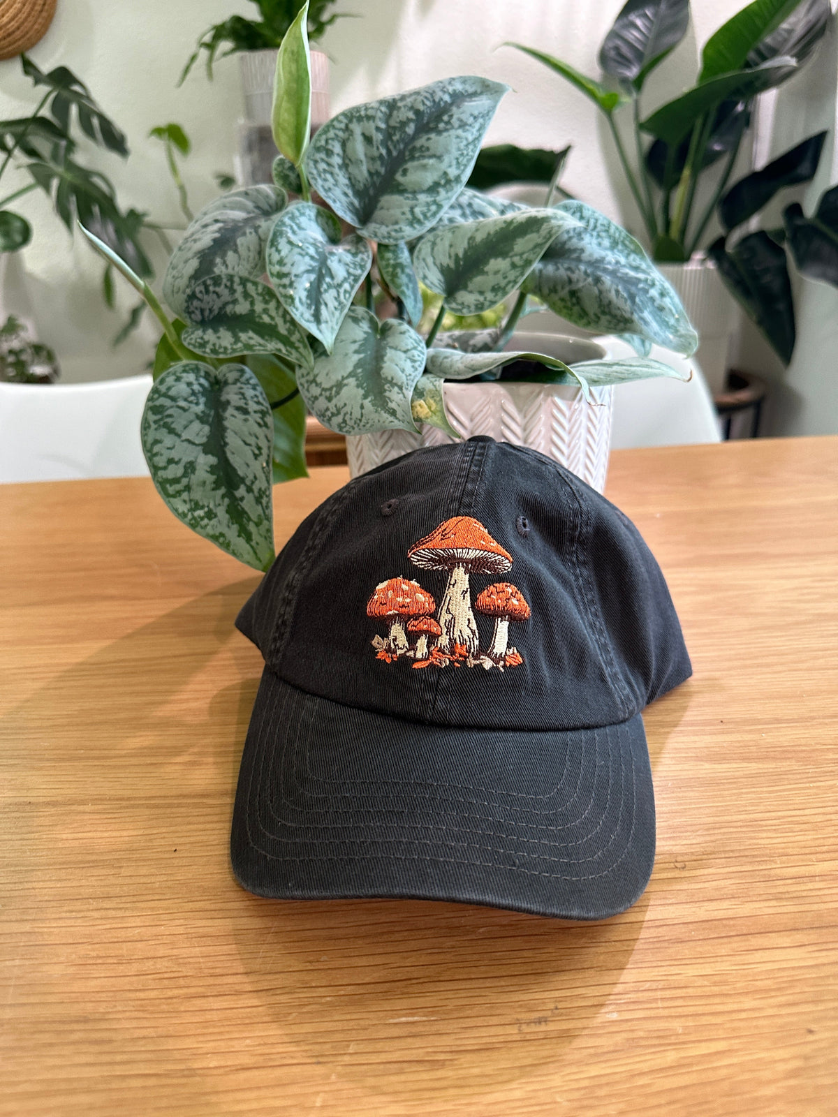Black baseball cap with orange mushroom patch embroidery, curved brim