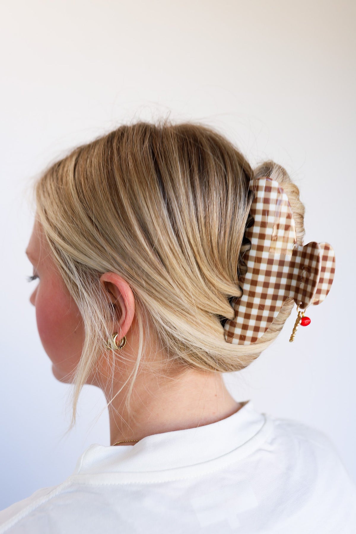 Brown gingham hair claw with red tomato charm clipped into a blonde bun