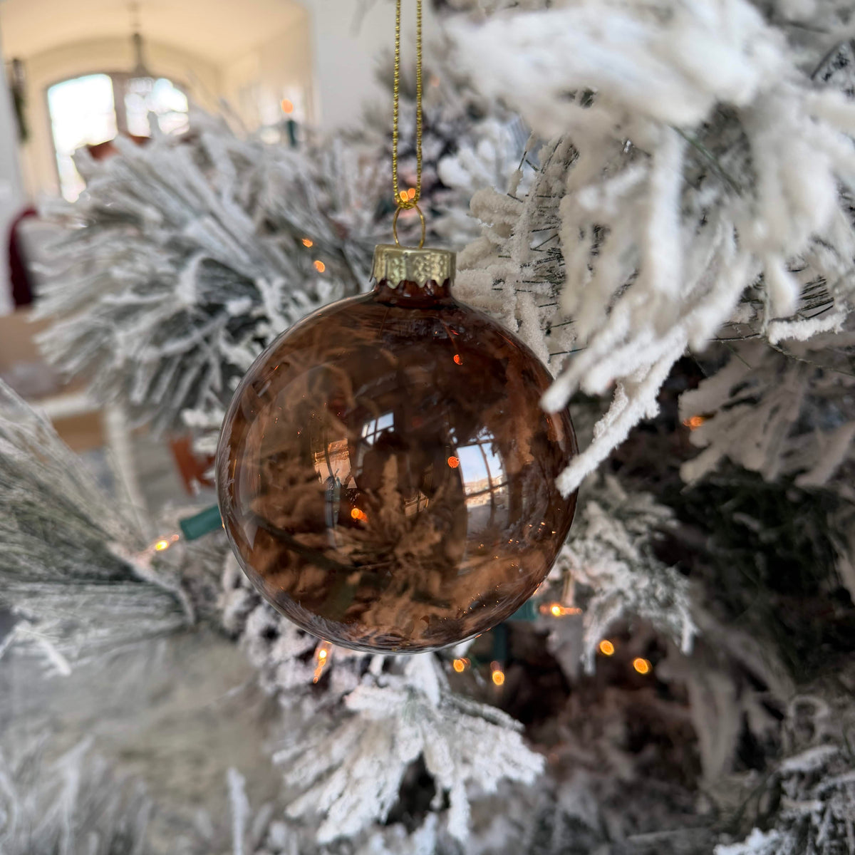 Large smoky brown glass ornament ball hanging on a decorated Christmas tree