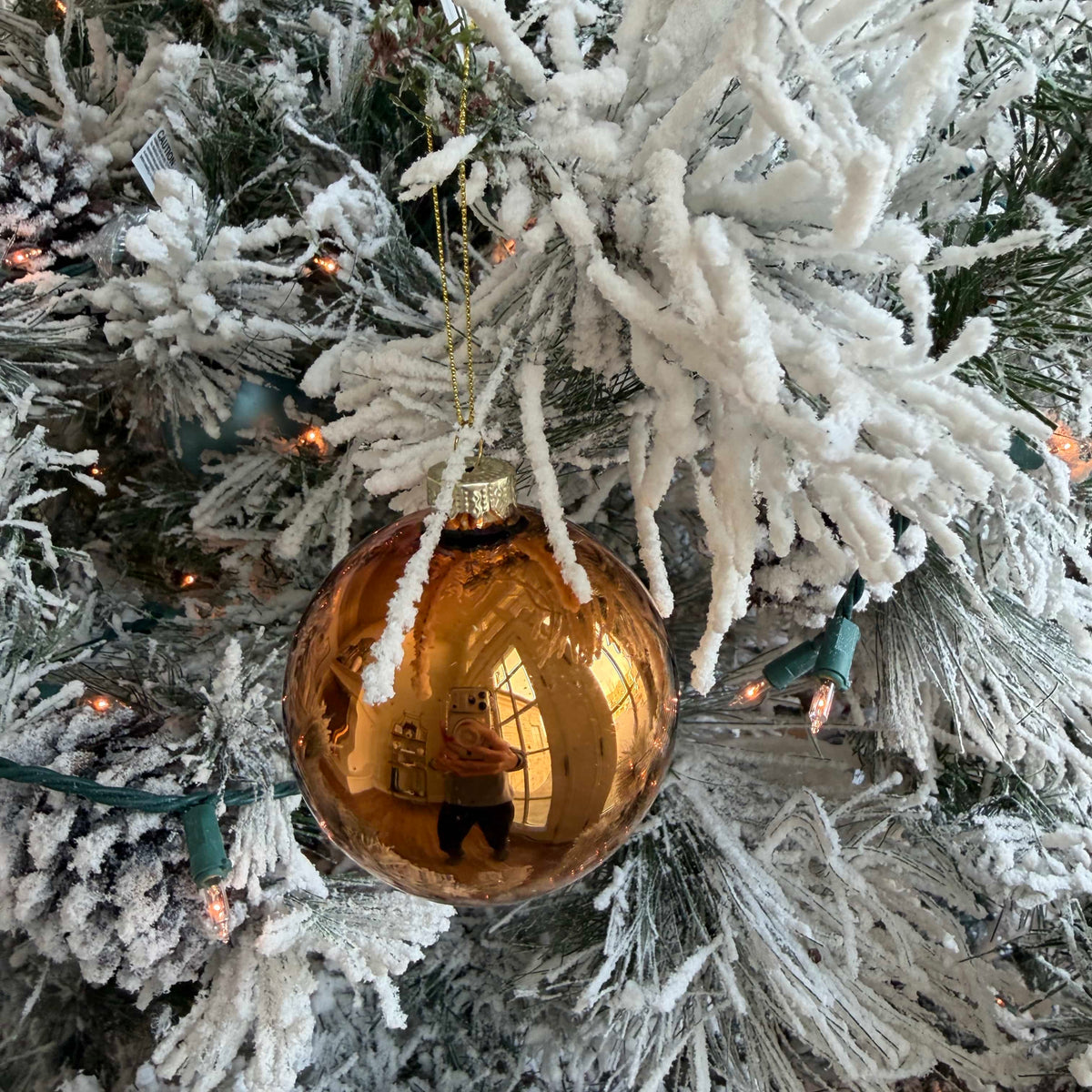 Large amber-brown glass ornament ball hanging on a snow-covered Christmas tree