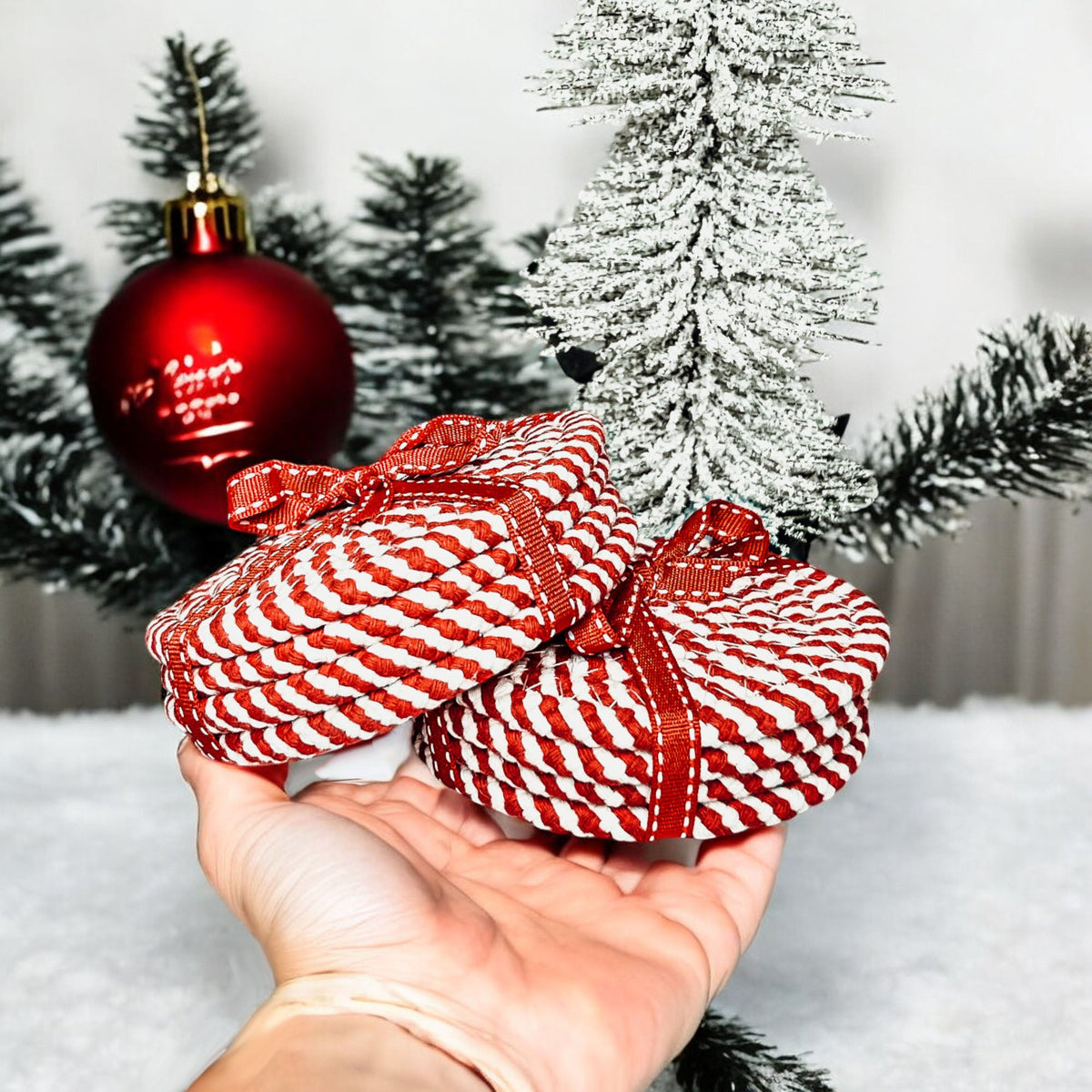 Round woven coasters with red-and-white striped pattern, tied bundle in hands