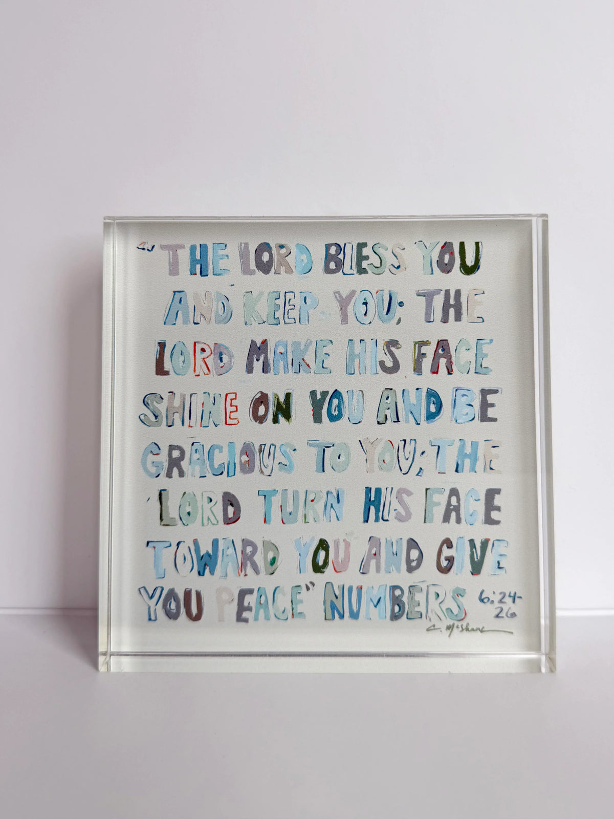 Clear acrylic tabletop art with blue scripture text, shown at an angle.