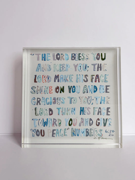 Clear acrylic tabletop art with blue scripture text, shown at an angle.