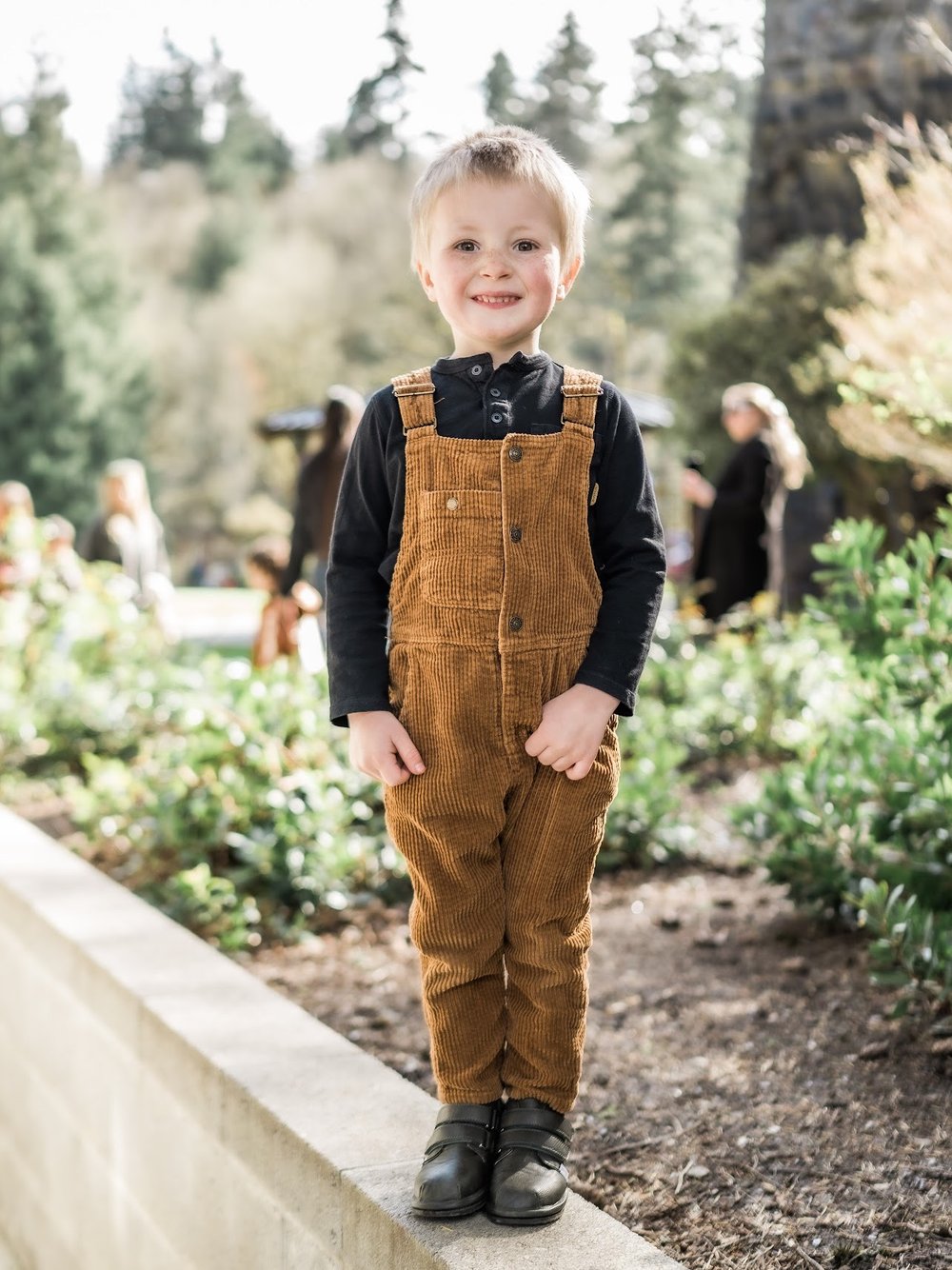 Toddler standing in dark sneakers with two hook-and-loop straps and rubber sole