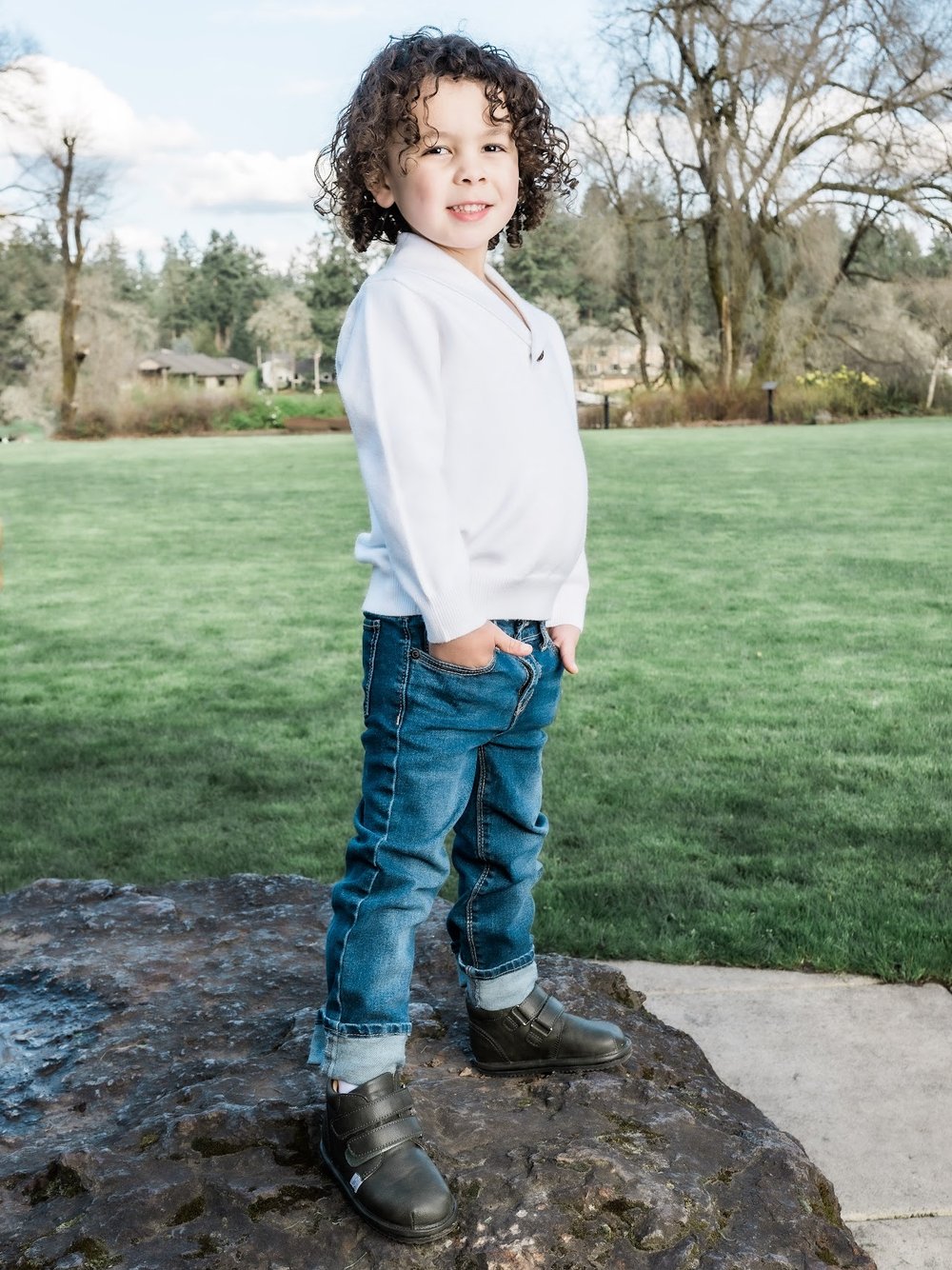 Toddler standing wearing dark sneakers with hook-and-loop straps and low-profile sole