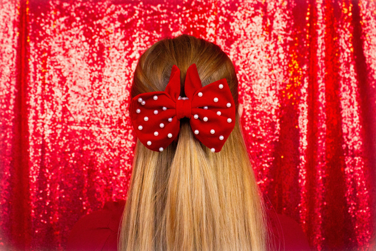Red bow hair claw with pearl dots, centered on hair bun