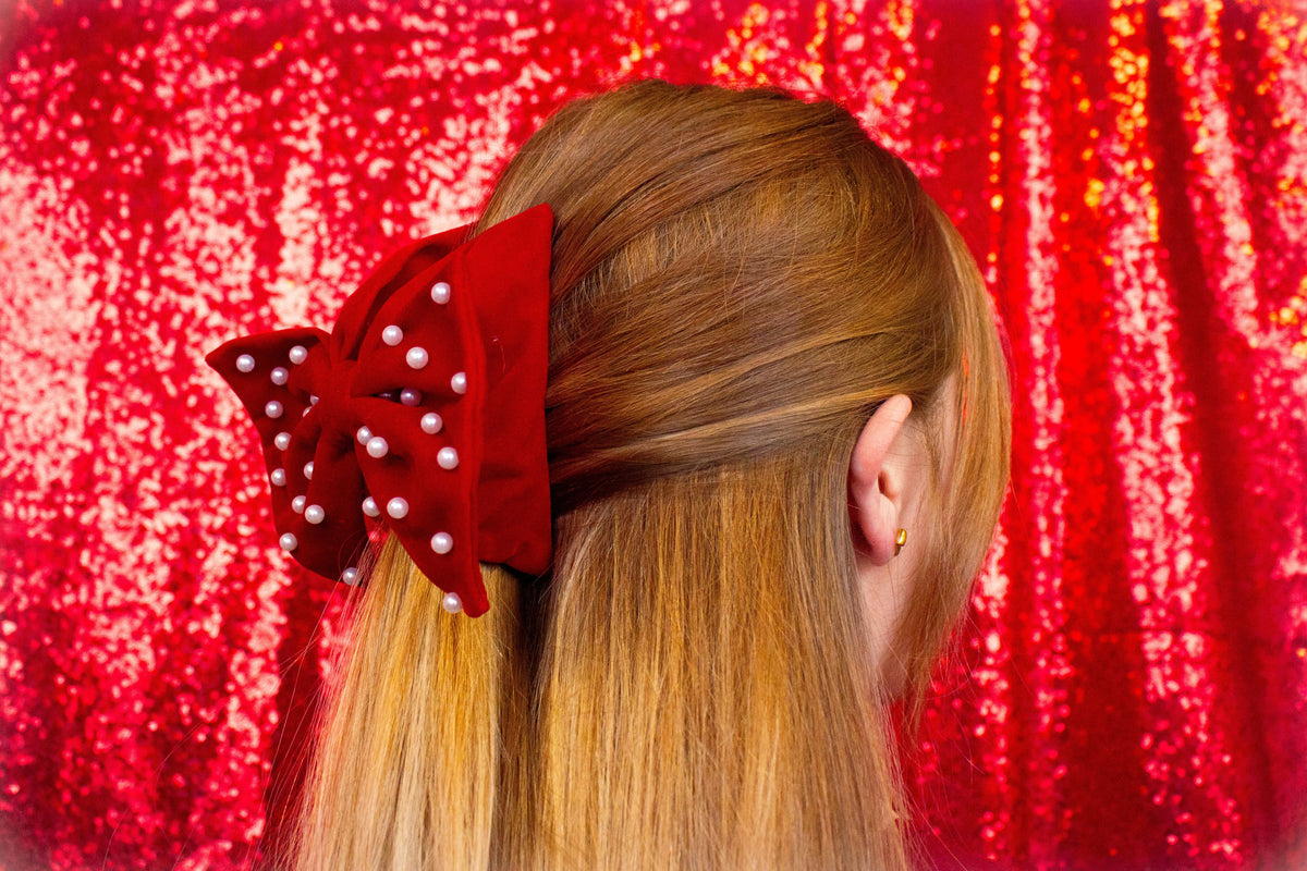 Red velvet bow hair claw with pearl dots and center tie on brown hair