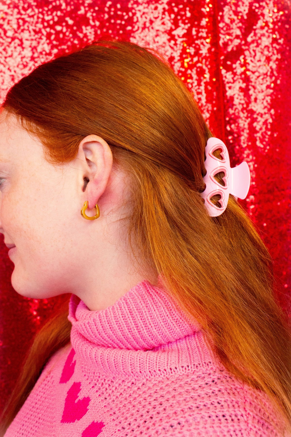 Pink heart-shaped hair claw with swirl cutouts, clipped to long hair