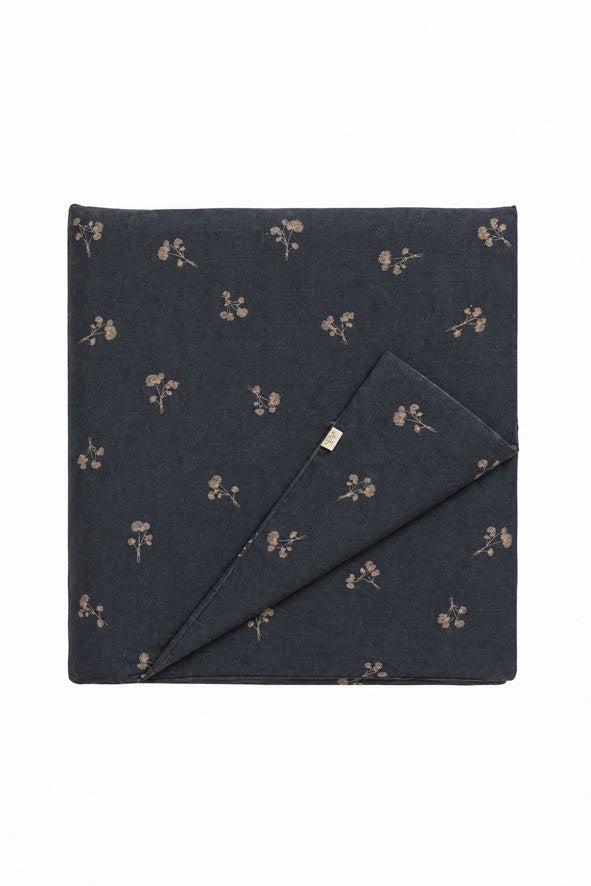 Blue quilted crib blanket with a small dandelion print and folded corner