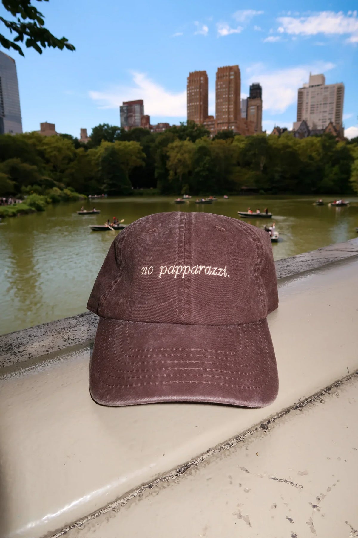 Brown baseball cap with front 'no papparazzi' embroidery and curved brim