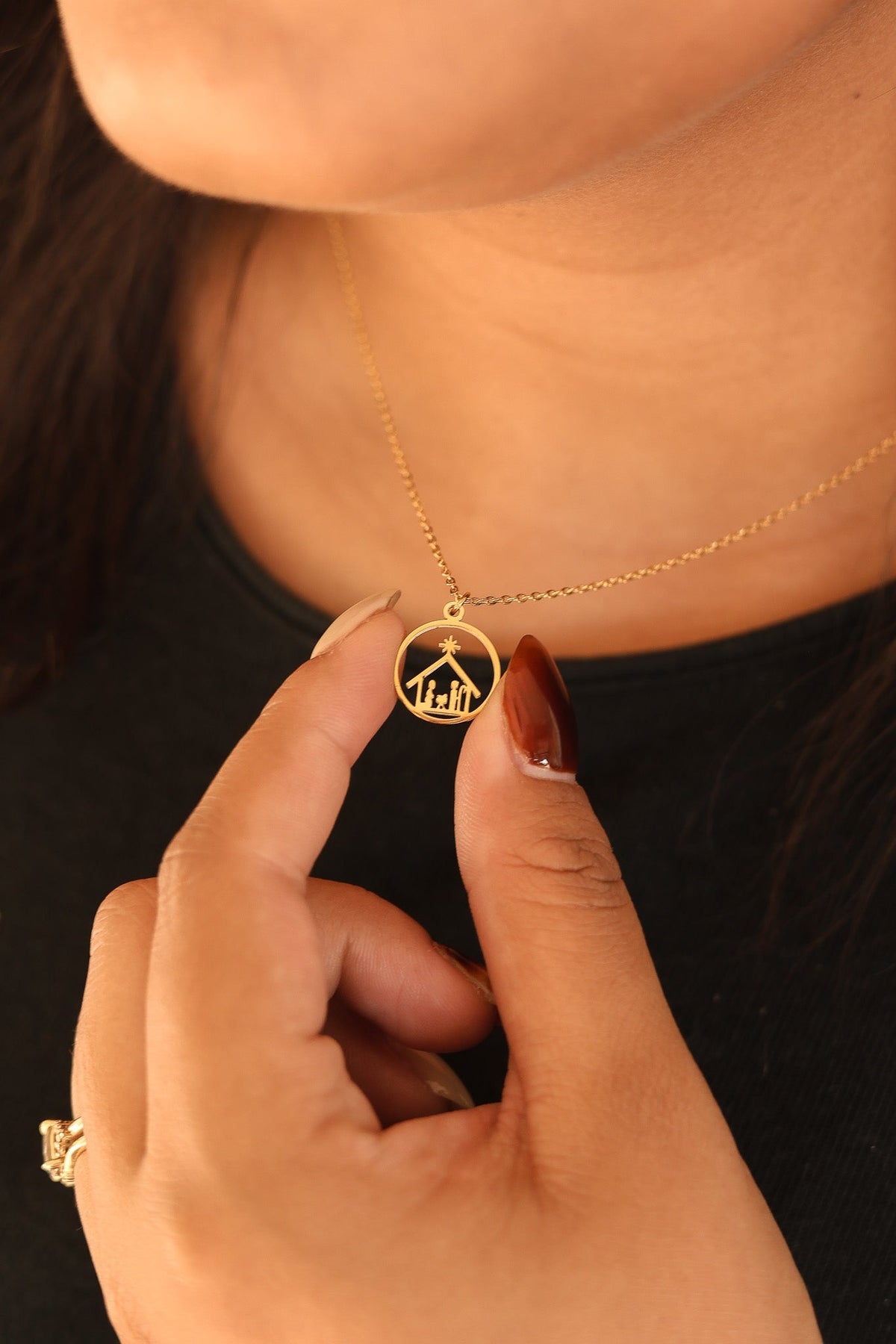 Gold Nativity necklace with round scene pendant, held at the neck