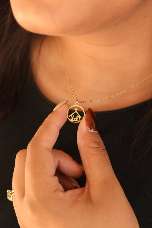 Gold Nativity necklace with round scene pendant, held at the neck