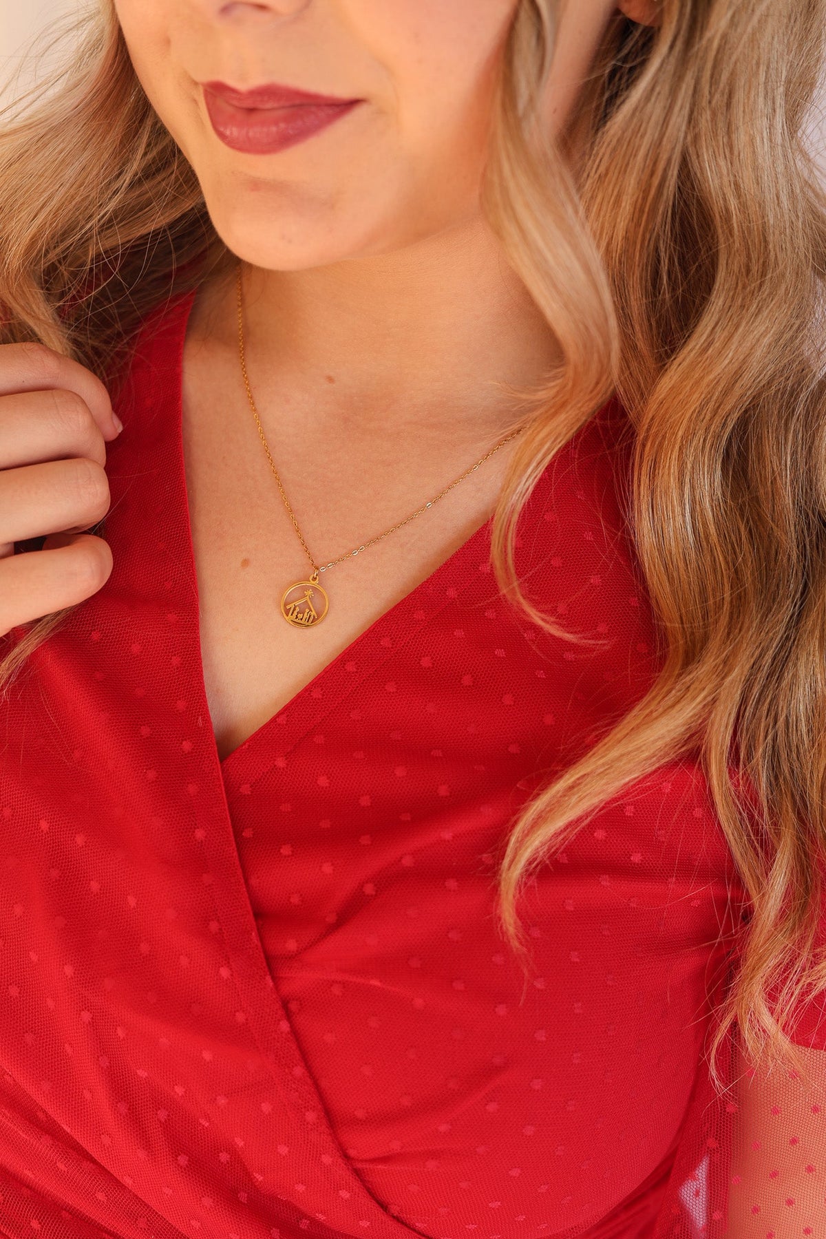 Gold Nativity necklace worn with a red V-neck dress