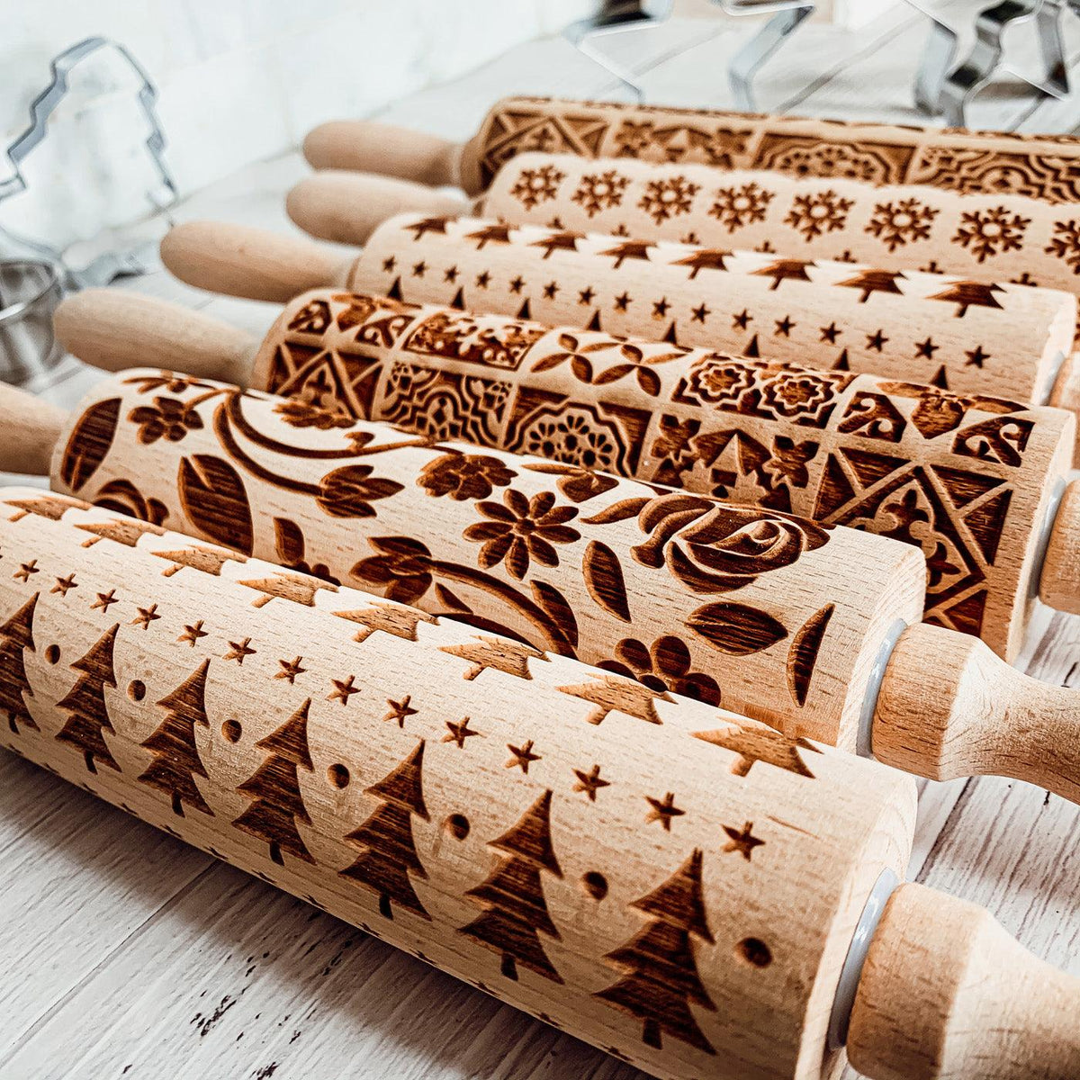 Close-up of wooden rolling pin barrels with ornate snowflake and star etched patterns