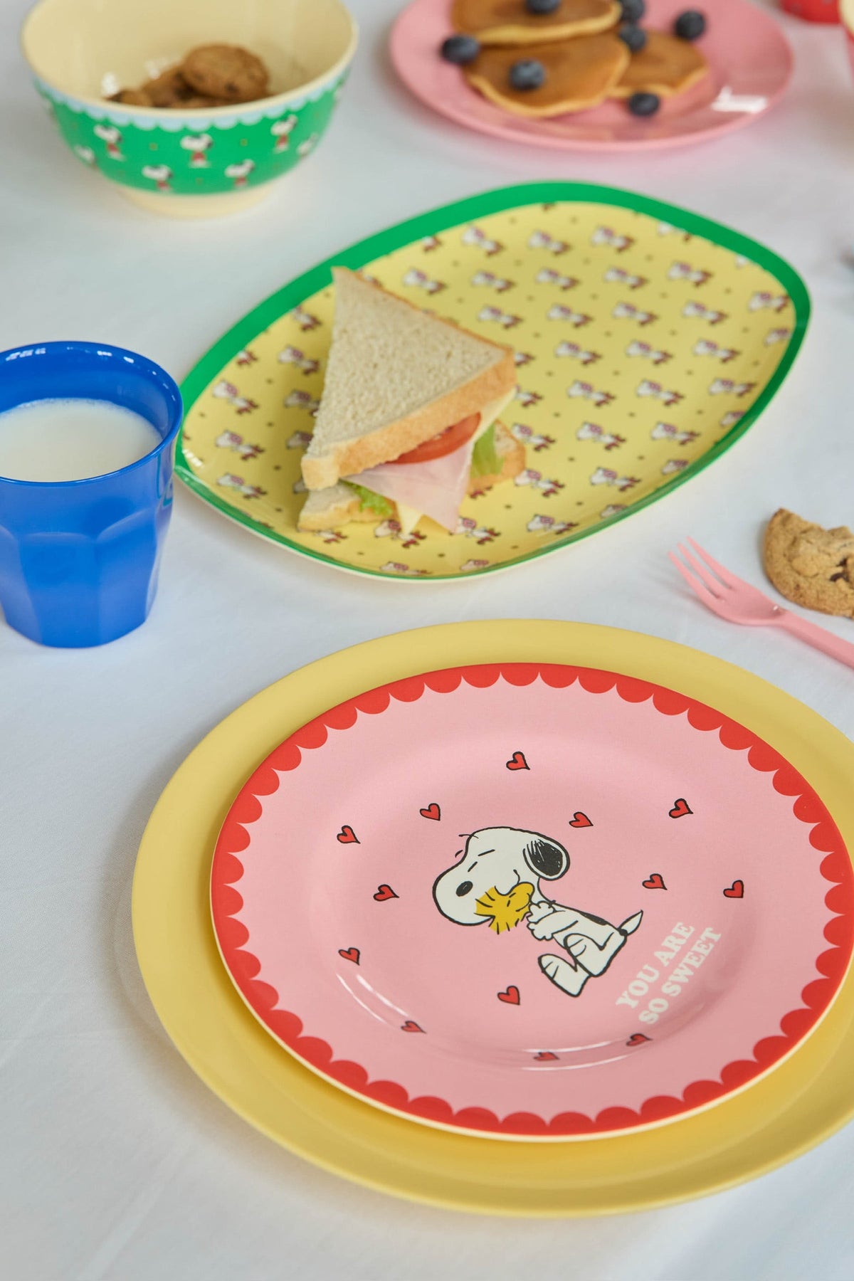 Yellow oval Snoopy plate with green rim and sandwich pieces