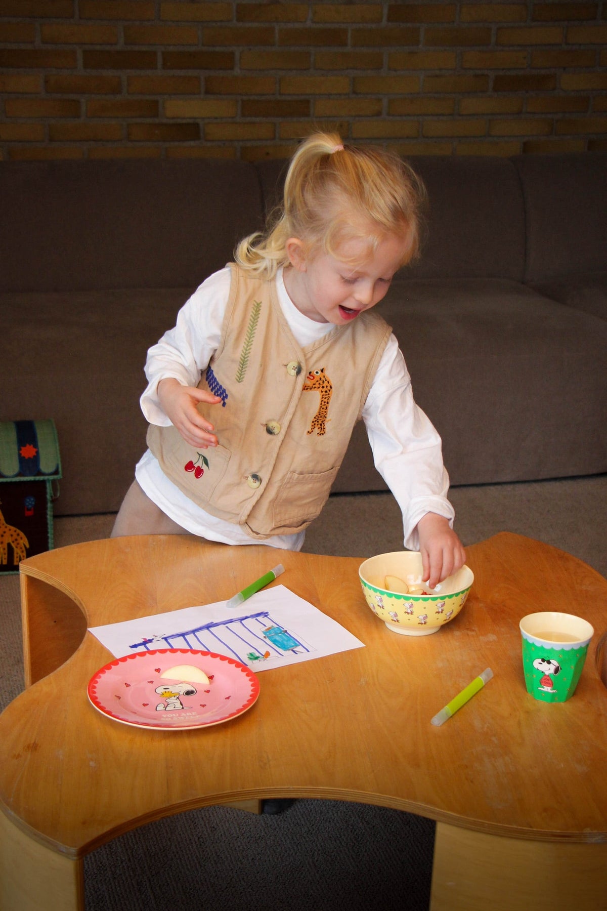 Green Snoopy melamine cup in front of a child during mealtime