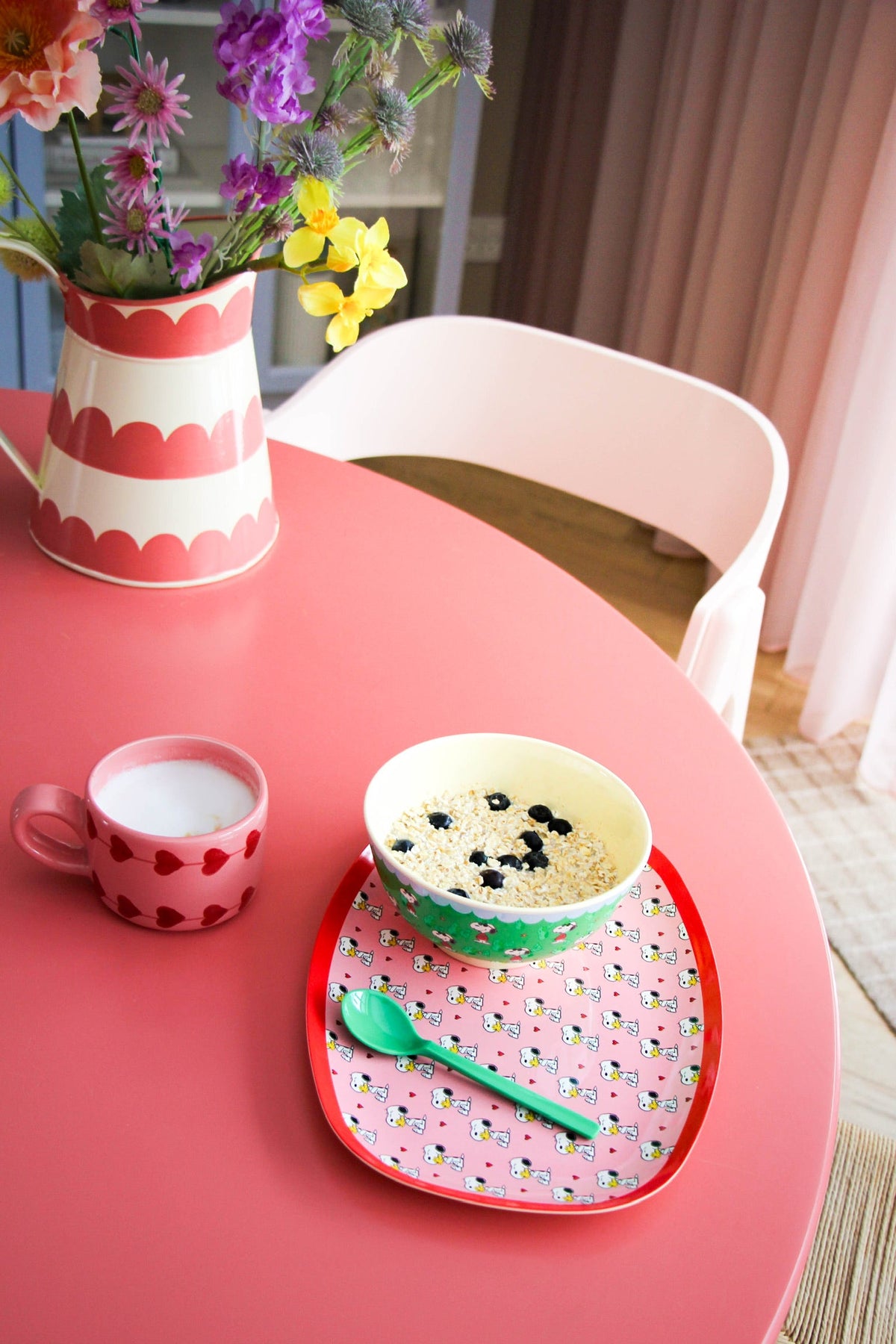 Green Snoopy-printed bowl with cookies inside on a mat