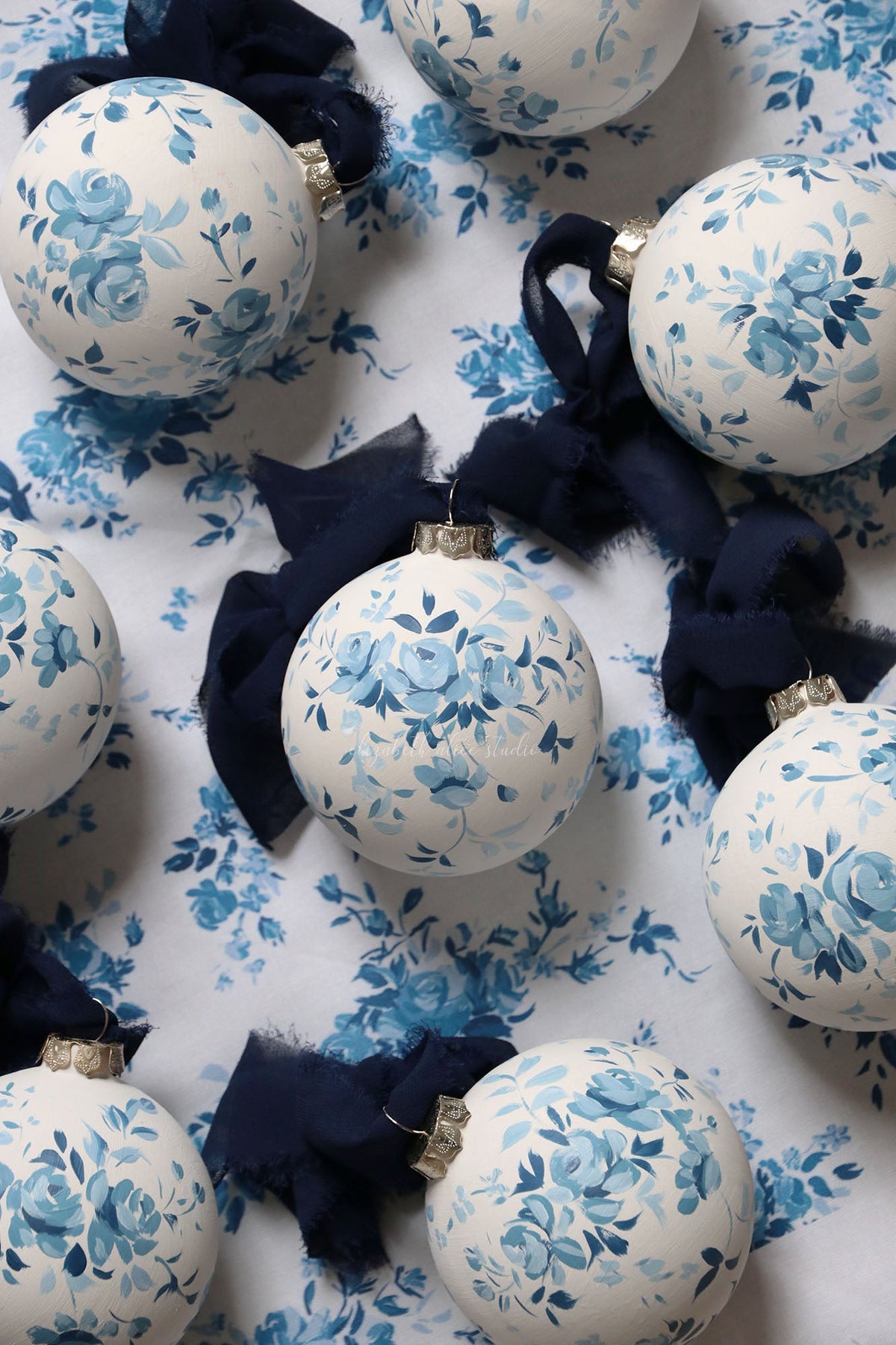 Hand-painted white ornament with blue vintage roses and a navy fabric bow