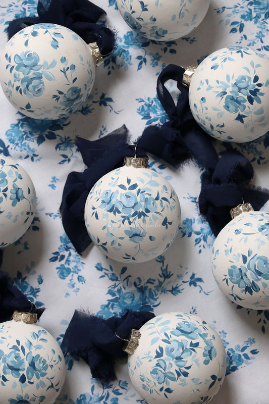 Hand-painted white ornament with blue vintage roses and a navy fabric bow