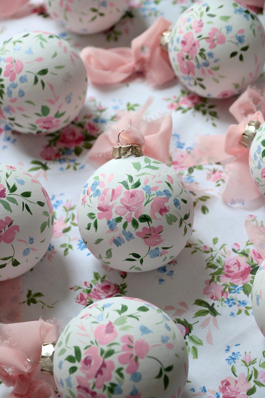 White Christmas ornament with hand-painted pink roses, green leaves, and metal hanging cap