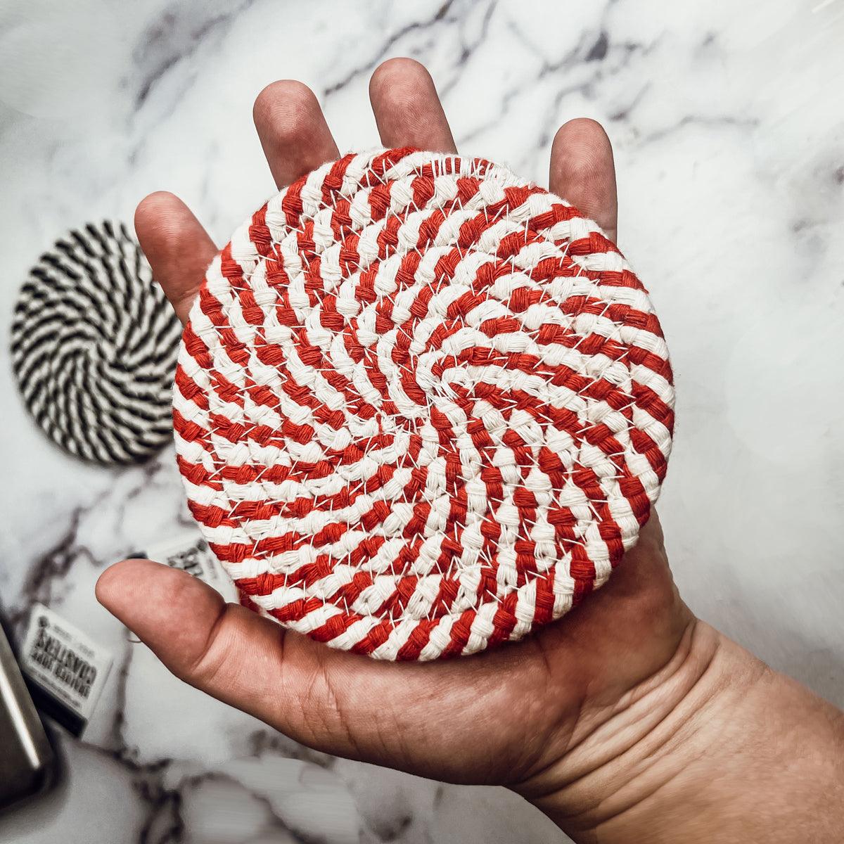 Set of 4 red-and-white braided rope coasters with striped pattern, held in hand